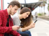 Dos jóvenes contemplan la pantalla de su teléfono.