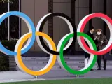 Los Aros Olímpicos, en Tokio, junto a una mujer con mascarilla.
