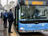 Un agente de la Policía Municipal de Madrid reparte mascarillas a los pasajeros de un autobús de la línea 9 de la EMT