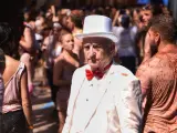 Un hombre vestido con un traje y un sombrero blanco, pasea por una calle de Buñol, durante la fiesta de la Tomatina de Buñol 2019.