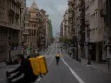 Dos trabajadores de Glovo en bicicleta por una calle de Barcelona, prácticamente vacía durante el primer día laborable de la segunda semana desde que se decretó el estado de alarma, en Barcelona/Catalunya (España) a 23 de marzo de 2020.