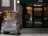 Un repartidor de Amazon con una mascarilla por la pandemia de coronavirus lleva un cargamento de paquetes a un edificio de apartamentos de Manhattan, en Nueva York.