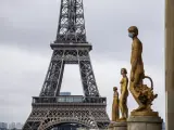 Las estatuas doradas de la Plaza de Trocadero, en Par&iacute;s, aparecen este domingo adornadas con mascarillas de protecci&oacute;n, con la Torre Eiffel de fondo.