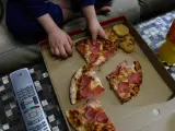 Un niño come pizza del menú infantil de Telepizza mientras ve la televisión en su casa