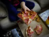 Un niño sostiene un trozo de pizza del menú infantil de Telepizza en el barrio de San Fermín en el distrito de Usera, cadena que, junto a Rodilla, reparte un menú escolar a más de 11.500 alumnos beneficiarios de beca comedor en la Comunidad de Madrid.