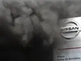 El humo producido por la quema de neumáticos, realizada por los trabajadores, casi tapa el logo de Nissan, a la entrada de la planta de la Zona Franca de Barcelona.
