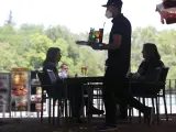 Un camarero protegido con mascarilla atiende a una mesa de una de las terrazas abiertas en el Parque de El Retiro