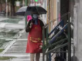 Una mujer se protege de la lluvia bajo su paraguas durante una tormenta en una imagen de archivo.