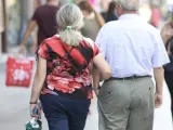 Un pareja de jubilados pasea del brazo.