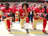 Colin Kaepernick, en el centro, arrodillado como protesta durante la audición del himno de Estados Unidos.