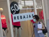 Una persona pasa al lado de un escaparate de una tienda de la capital con carteles de descuentos durante el segundo día de rebajas, en Madrid (España), a 26 de junio de 2020.