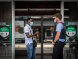 Un Mosso d'Esquadra habla con un hombre en la entrada de la Estación de Tren de Lleida.