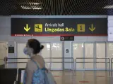 Una persona con mascarilla pasa junto a la entrada de la sala de llegadas 1 de la Terminal 1 del Aeropuerto de Barajas, en Madrid (Espa&ntilde;a) a 4 de julio de 2020.