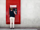 Una mujer saca dinero de un cajero del Banco Santander.