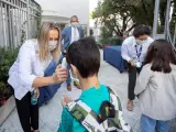 na trabajadora toma la temperatura a un niño a la entrada del colegio privado internacional American School of Barcelona.