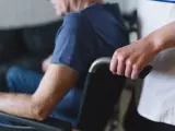 cuidador empujando la silla de ruedas de un anciano