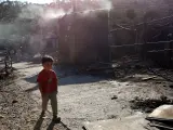 Un niño pasa junto a un cobertizo, todavía humeante, tras el incendio que ha arrasado gran parte del campo de refugiados de Moria, en Lesbos (Grecia).