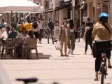 Personas paseando con mascarillas y sentadas en terrazas en una céntrica calle de Vitoria-Gasteiz.