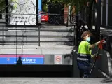 Una trabajadora limpia un acceso al metro en el distrito de Vicálvaro, en una de las 8 nuevas zonas de Madrid con restricciones de movilidad por el coronavirus.