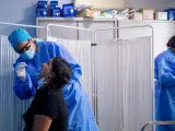 Un trabajador sanitario protegido le realiza a una mujer un test PCR.