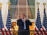 El presidente de EE UU, Donald Trump, se quita una mascarilla al saludar desde un balc&oacute;n de la Casa Blanca, tras regresar a su residencia despu&eacute;s de ser hospitalizado por COVID-19.