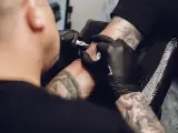 Un tatuador realizando un tatuaje.