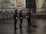 Agentes de policía piden la documentación a una persona, durante la primera noche del toque de queda impuesto en Milán, Italia, para frenar el avance de la pandemia del coronavirus.