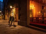 Una pareja con mascarillas pasa por delante de un restaurante cerrado en Barcelona.