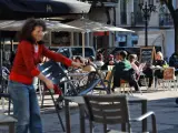 La propietaria de un bar de Barcelona monta la terraza en el primer d&iacute;a de reapertura de la restauraci&oacute;n en Catalunya.