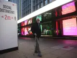 Un hombre con mascarilla por el coronavirus pasa junto a tiendas con decoración navideña en Londres, Reino Unido.