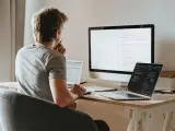 Un hombre teletrabajando con varios ordenadores