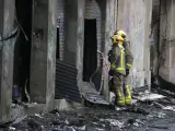 Dos bomberos observan el interior de la nave incendiada en Badalona, en una inspección este viernes 11 de diciembre de 2020.