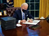 El presidente de EE UU, Joe Biden, firma sus primeras órdenes ejecutivas en el Despacho Oval de la Casa Blanca.