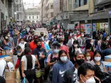 Cientos de personas con mascarillas por el coronavirus, en un mercado de Lima, Perú.