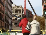 Dos vecinos observan los trabajos de demolición en el edificio de la calle Toledo, en Madrid.