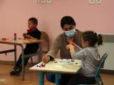 Una profesora con mascarilla atiende a una alumna.