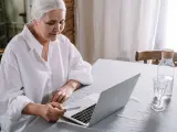 Una mujer mayor consulta su ordenador portátil en su casa.