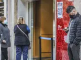 Un joven mira su teléfono móvil mientras espera para entrar en una oficina del SEPE (antiguo INEM), en Valencia