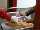 Un voluntario (i) trae comida a una persona (d) como parte del reparto diario de alimentos del Comedor Social San José, en Puente de Vallecas, Madrid (España), a 5 de febrero de 2021.