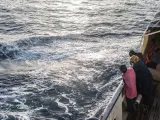 Refugiados y migrantes miran por la borda en el Mediterráneo desde la borda del Open Arms tras un rescate realizado la semana pasada.