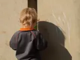 Imagen de archivo de un niño jugando al escondite.