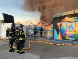 Los Bomberos tratan de apagar un incendio en una cuatro naves industriales, en la calle Monasterio de las Huelgas, en el barrio de Fuencarral (Madrid).
