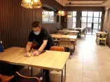 Un hombre prepara una mesa en un restaurante de Lleida.