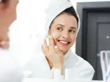Joven se aplica crema en el rostro frente al espejo