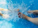 Dos personas chapotean con los pies en una piscina, en una imagen de archivo.