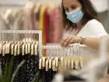 Archivo - Mujer con mascarilla en una tienda de ropa.