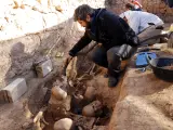 Arqueólogos trabajan en la fosa de la Guerra Civil de Soleràs (Lleida). Se observan restos óseos amontonados.