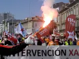 Decenas de personas con banderas de sindicatos y humo durante una manifestación