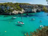 Aguas claras en un entorno privilegiado con acantilados cubiertos de pinos. Este peque&ntilde;o para&iacute;so en Menorca no es de acceso f&aacute;cil porque solo se puede llegar por mar o a pie, pero merece mucho la pena visitarlo. En verano hay mucha gente, pero a primera hora del d&iacute;a se pude disfrutar de la tranquilidad de un lugar inigualable.