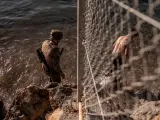 Un soldado del ejército ayuda a un inmigrante a su llegada a la playa de El Tarajal en Ceuta